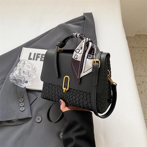 Minimalist black leather top handle handbag with woven base and polka dot silk scarf detail