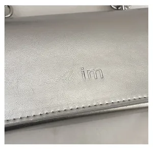 Close-up of matte silver chain bag with mim logo and fine leather texture finish
