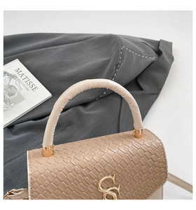 Close-up of beige snake embossed handbag featuring a stylish gold interlocking logo
