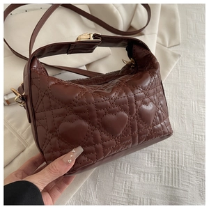 Detail of dark brown heart quilted crossbody bag with gold metal buckle and strap