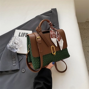 Green and brown crossbody bag with gold lock and silk scarf on business blazer