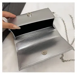 Detailed view of silver metallic bag featuring a magnetic snap closure and chain strap