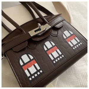 Detail of dark brown crocodile embossed tote bag with unique arch window patterns and silver lock