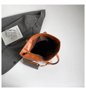 Detail of a large brown tote bag with an included checkered zip pouch on a suit background
