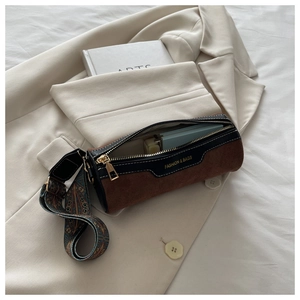 Detail view of cylinder bucket bag with brown suede, ethnic strap and interior capacity