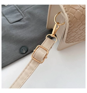 Close-up of beige leather bag strap with gold metal buckle and embossed texture detail