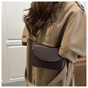 Detail of vintage dark brown crossbody bag with embossed logo and fine stitching