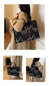 Detail of embroidered tote bag featuring white wave patterns and fashion label patch