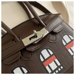 Detail of a dark brown leather handbag featuring colorful window patterns and silver turn-lock