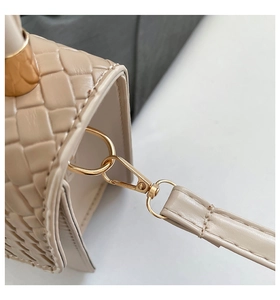 Macro view of apricot woven leather bag showing classic texture and gold metal buckle