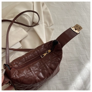 Close-up of heart-shaped quilted pattern and golden zipper on dark brown leather handbag