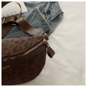 Détail du sac de poitrine léopard avec zips dorés et sangle réglable sur fond denim