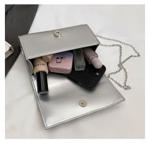 Macro shot of silver metallic crossbody bag interior with phone and cosmetics