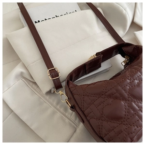 Detailed view of dark brown quilted handbag featuring heart-shaped stitching and gold hardware