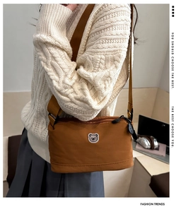 Close-up of brown nylon crossbody bag featuring a cute bear embroidery and wide strap