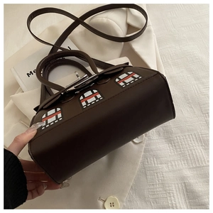 Detail of dark brown leather handbag with colorful architectural window patterns and silver lock