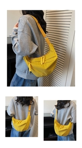 Detail of a bright yellow nylon crescent crossbody bag with woven zipper pullers