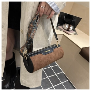Close-up of brown corduroy cylinder bag with bohemian pattern wide strap and gold logo