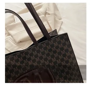 Close-up of the textured synthetic leather tote bag with elegant M-letter monogram prints