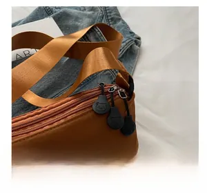 Detail of a brown shoulder bag featuring a smooth zipper with a cute bear-shaped puller