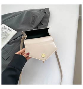 Detail of a cream faux leather square bag with gold magnetic buckle and slim shoulder strap