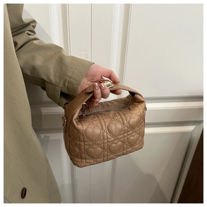 Detail of khaki quilted handbag with heart embroidery pattern and zip closure