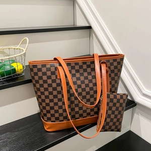 Checkered tote bag and pouch set with orange leather trim on black wooden stairs