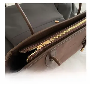 Close-up of smooth gold metal zipper and vintage brown leather texture on tote bag