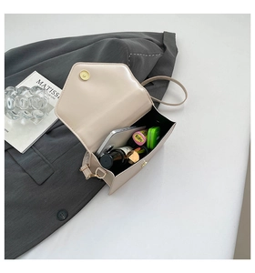 Detail view of cream flap bag interior showing practical space for phone and makeup