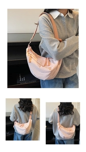 Detail of pink nylon crescent bag with wide strap and zip texture on female model