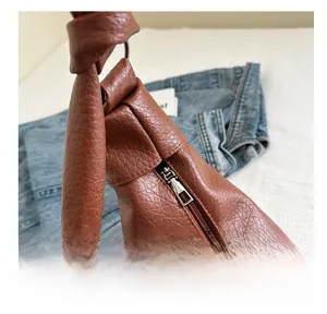 Macro detail of smooth silver metal zipper on caramel lychee texture PU shoulder bag