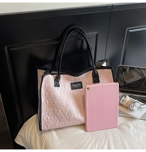 Pink quilted tote bag with colorful embroidery and black trim in a lifestyle setting