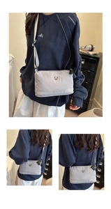 Detail of grey nylon crossbody bag with small bear embroidery and adjustable wide strap