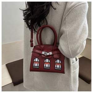 Detail of burgundy crocodile-textured mini bag with architectural window design and silver lock