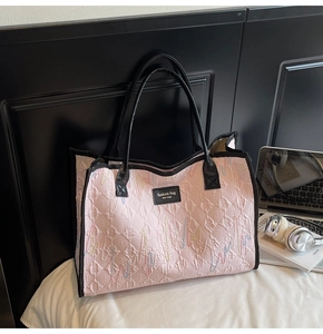 Detailed macro view of pink quilted tote bag with wave embroidery and leather fashion label
