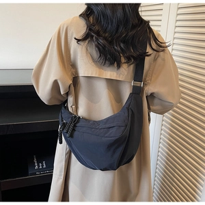 Detail of a black nylon crescent crossbody bag with adjustable wide shoulder strap and zippers