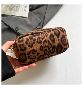 Gros plan sur un sac léopard en daim avec des bords en cuir marron et boucles dorées