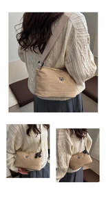 Detail of light khaki shoulder bag with round bear patch and wide adjustable strap