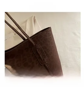 Detail of leopard print tote bag featuring faux suede texture and fuzzy doll charm