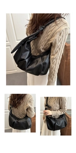 Detailed view of black pleated dumpling bag with soft lychee texture and knot shoulder strap