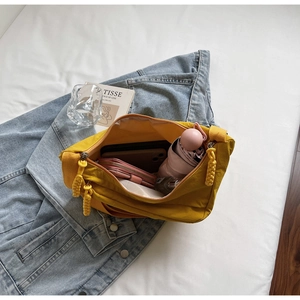 Detail showing high-capacity interior of yellow nylon crossbody bag on denim jacket