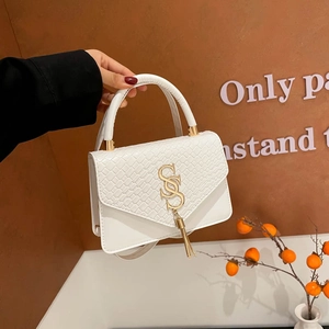 White crocodile embossed leather flap bag with gold S-buckle and tassel pendant detail