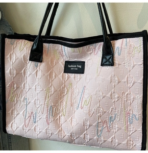 Detail of pink quilted tote bag with colorful wave embroidery and New York brand patch