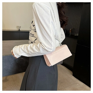 Close-up of pink patent leather crossbody bag with silver chain and metal knot handle