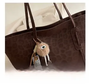 Detailed shot of leopard print tote bag with a whimsical furry plush toy charm accessory