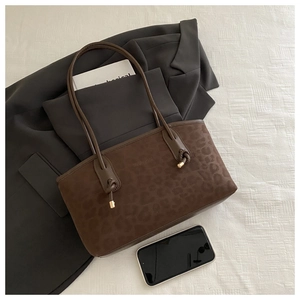 Detail of leopard print tote bag with brown suede texture and metal knotted strap tip