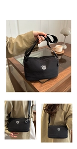 Detail of a black nylon crossbody bag with a cartoon bear patch and dual zippers