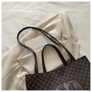 Detail of dark brown tote bag featuring all-over M monogram and embossed logo patch