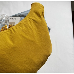 Detailed close-up of yellow nylon crescent bag with wrinkled texture on denim background