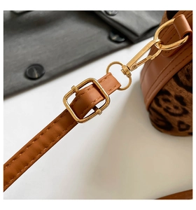 Détail de la bandoulière en cuir marron avec fermoirs dorés et accents à motif léopard